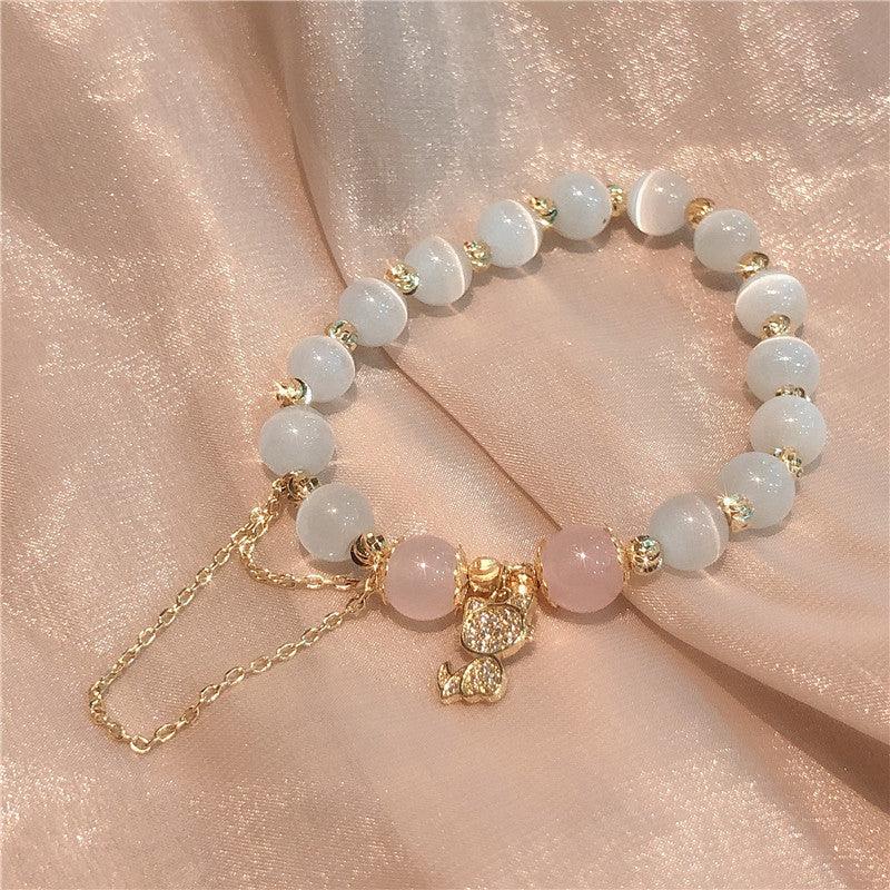 An elegant mix of pink gemstones and a gold cat pendant, blending traditional symbolism with modern chic.
