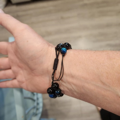 Black bead bracelet with dark blue accent beads worn on wrist, featuring a minimalist and modern design with spiritual significance.