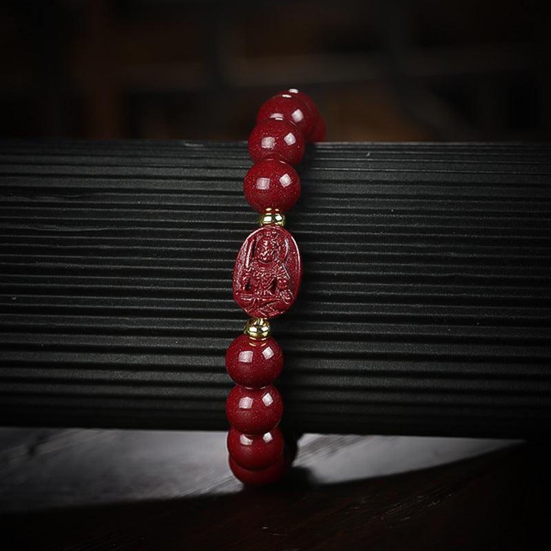 Close-up of red cinnabar beads and Buddha engraving, highlighting spiritual symbols on each bead.