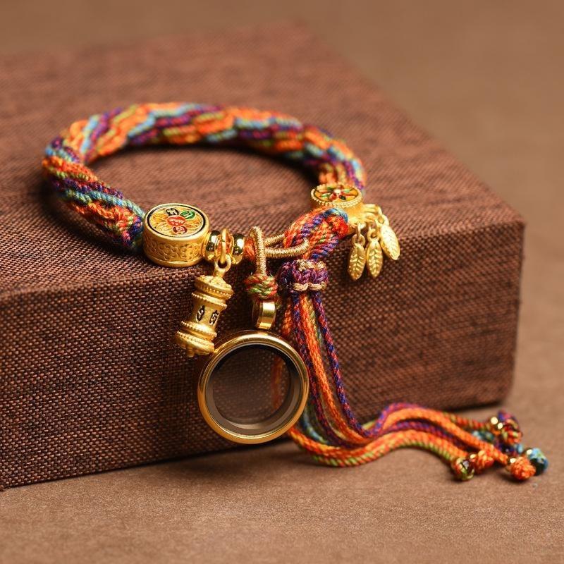 Close-up of the gold charms, including a prayer wheel and magnifying glass, adding spiritual significance to the vibrant woven design.