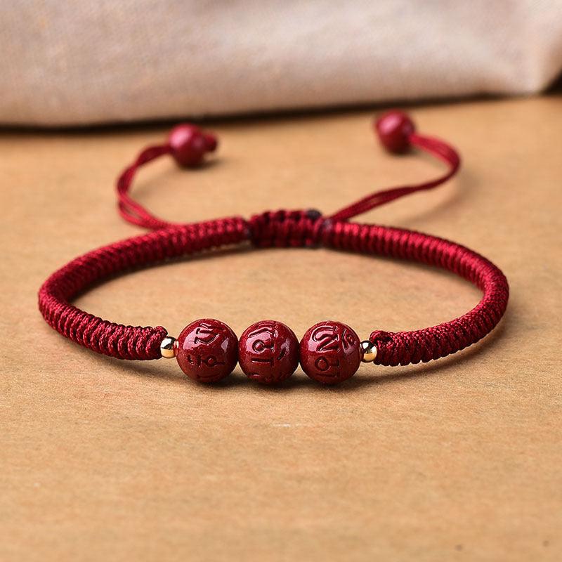 Close-up of the red cord and cinnabar beads, showcasing intricate engravings and vibrant color.
