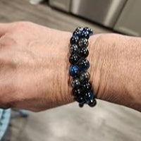 Close-up of wrist wearing a black and blue beaded bracelet, featuring tightly arranged beads for a bold and modern look