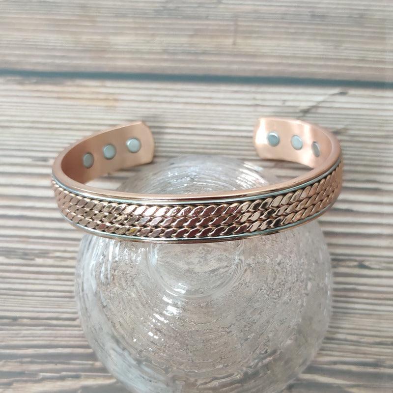 Copper magnetic bracelet with textured design, displayed on a clear glass surface to highlight its unique craftsmanship.