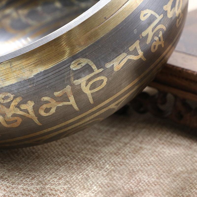 Craftsmanship-focused shot of the Tibetan Singing Bowl, highlighting the precision of the golden inscriptions.