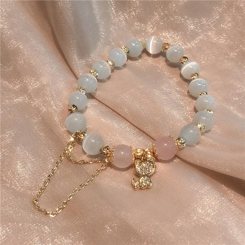 Delicate beaded bracelet with white and pink gemstones, adorned with a sparkling gold cat charm, perfect for adding a touch of elegance and whimsy.