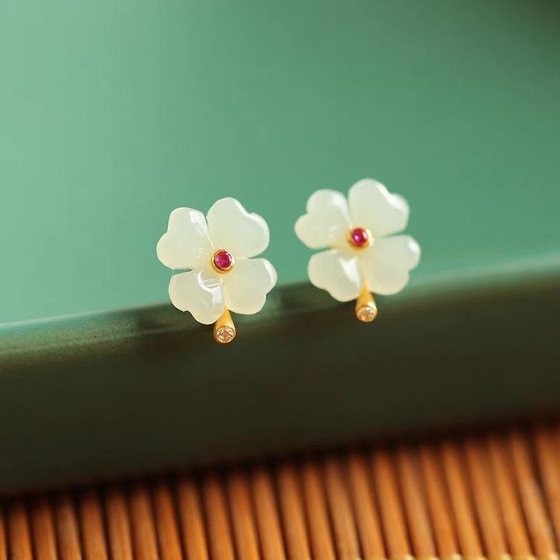 Delicate flower earrings crafted from translucent jade, with a golden stem and ruby-like center stone, symbolizing elegance and grace.