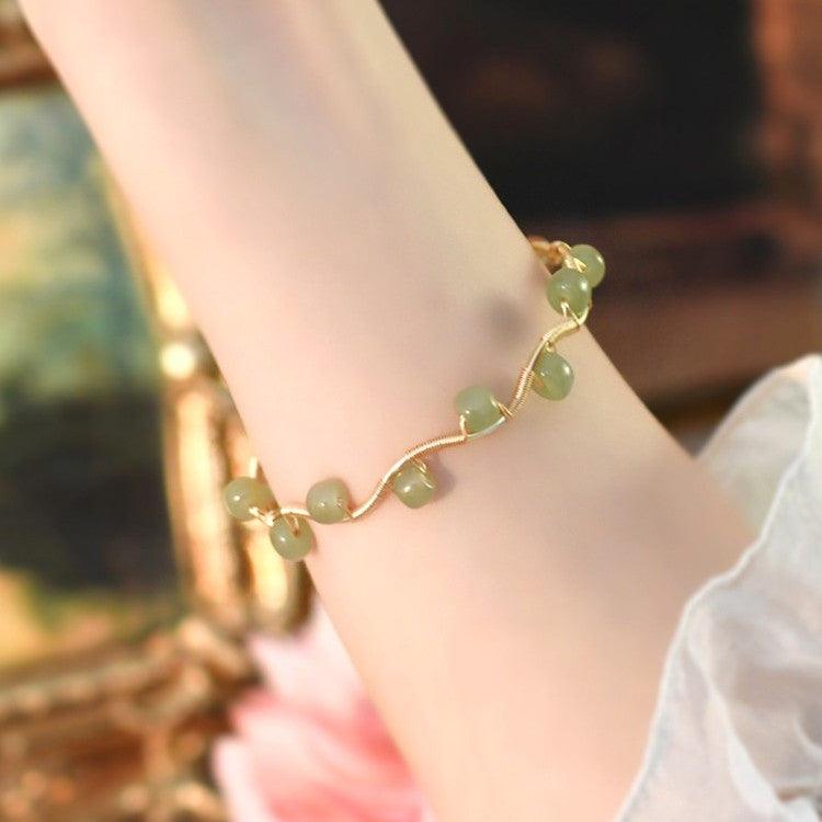 Delicate green gemstone bracelet with a gentle wave design on a gold chain.