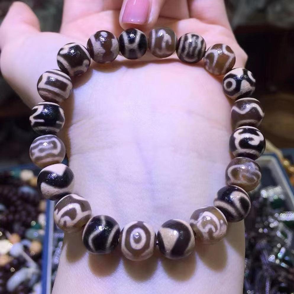 Detailed shot of Dzi bead texture, emphasizing the intricate, earthy patterns and grounding energy.