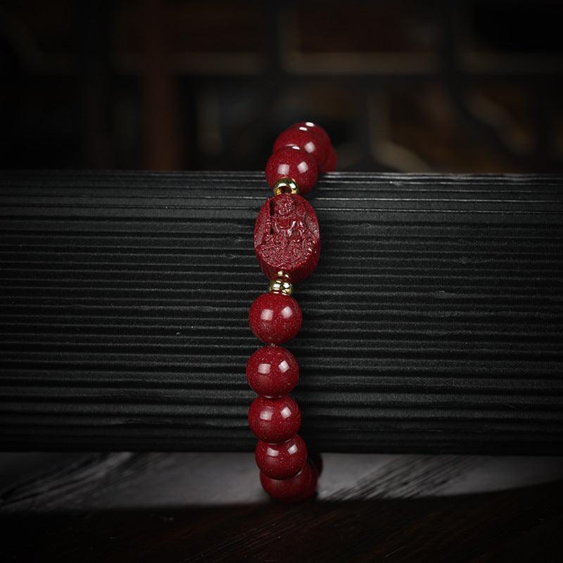 Detailed shot of the engraved Buddha on the cinnabar bead, highlighting the smooth finish and craftsmanship.