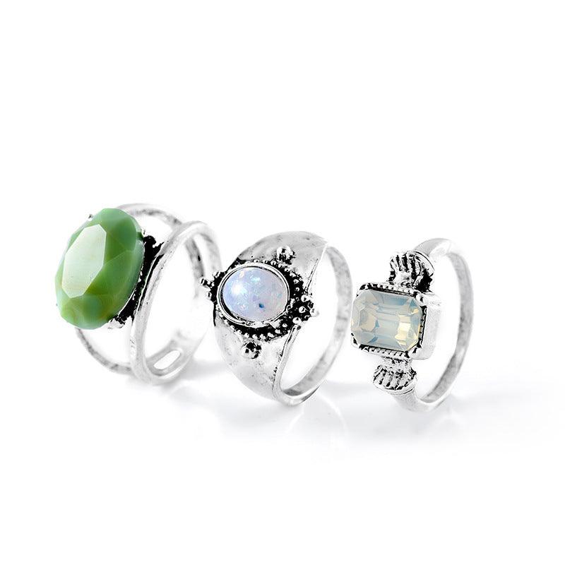 Detailed view of three gemstone rings, each with a distinct design—one with a green stone, another with opal, and the third with a clear gem.