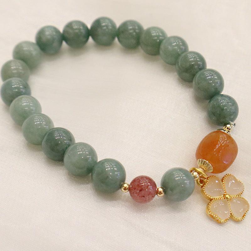 Elegant beaded bracelet with green, orange, and red stones, adorned with a four-leaf clover charm, symbolizing luck, prosperity, and balance.