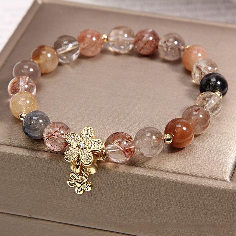 Elegant bracelet crafted from rutilated quartz with a golden floral charm, capturing the warm and grounding tones of the stones, a meaningful accessory for mindfulness.