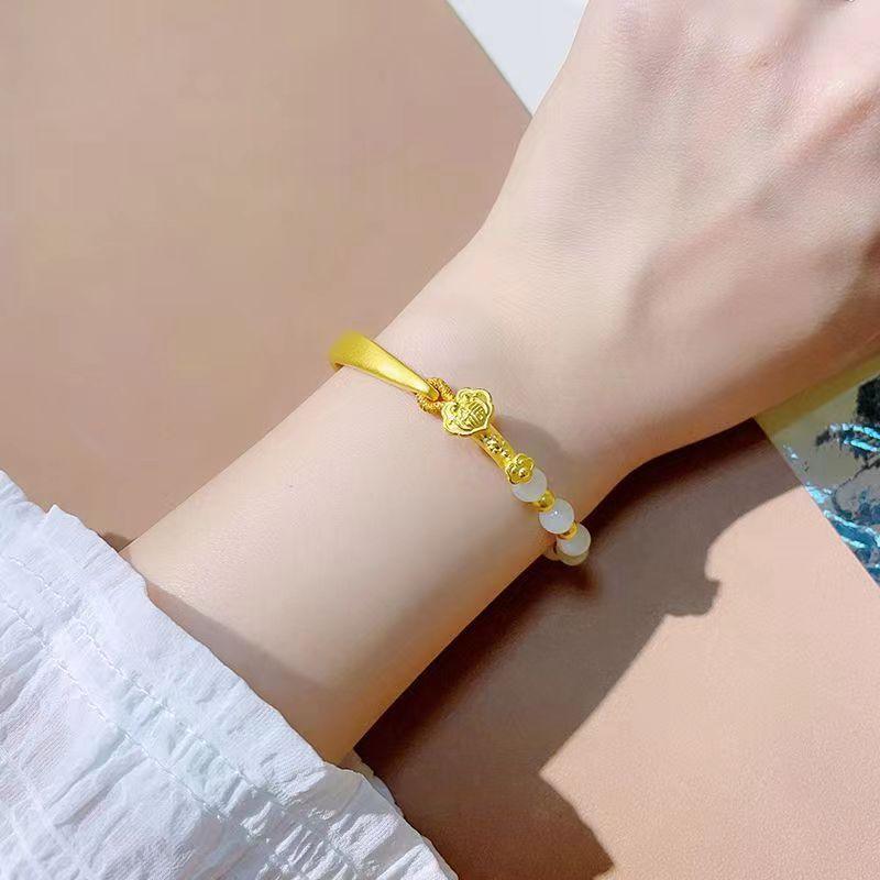 Elegant gold bracelet adorned with jade beads, symbolizing prosperity and protection, shown gracefully on a wrist.