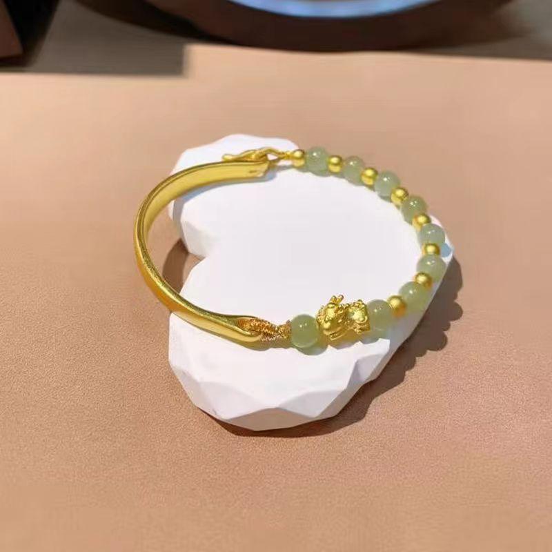 Elegant jade and gold bangle with delicate gold beads and Pixiu charm, symbolizing wealth, protection, and good fortune in Chinese culture.