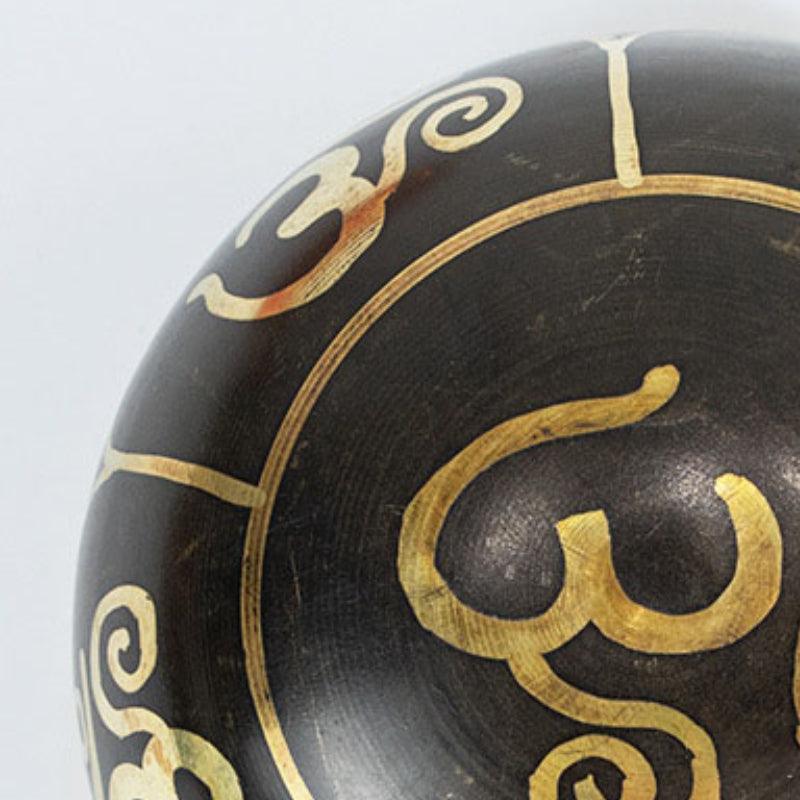 Elegant singing bowl set with an intricately carved bowl and smooth wooden mallet, emphasizing Tibetan artisanship and precision.