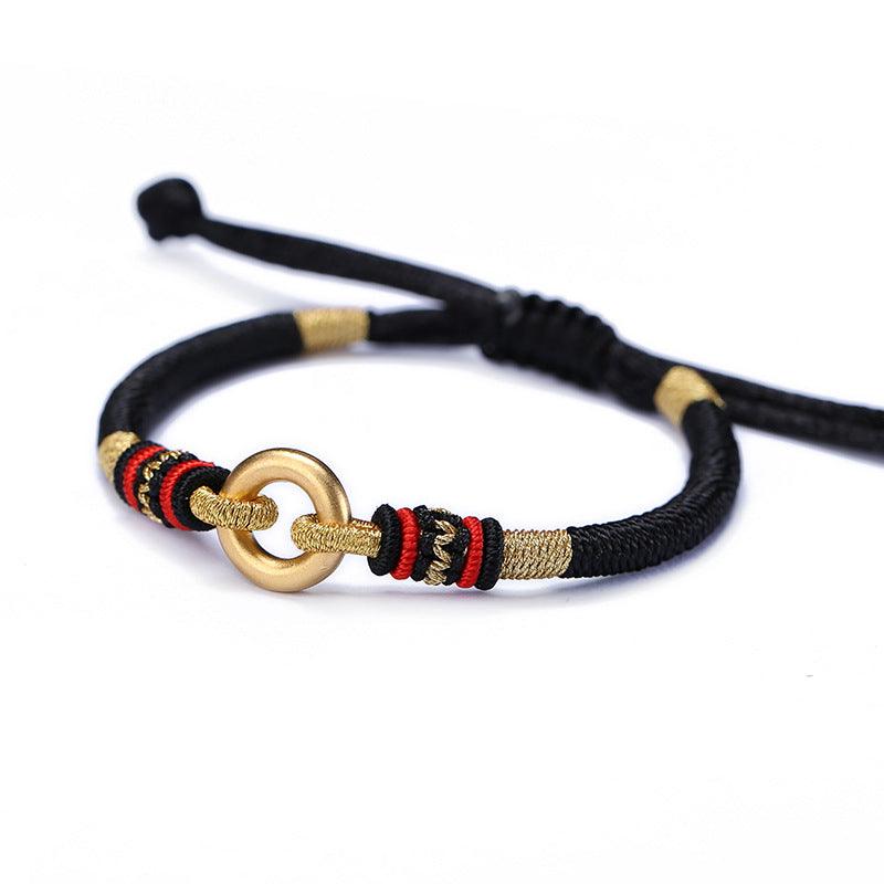 Full view of Tibetan-style black woven bracelet with a gold ring accent, symbolizing strength, protection, and cultural significance.