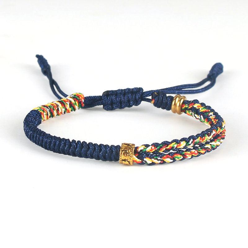 Full view of Tibetan-style blue woven bracelet with multicolored cord and brass accents, symbolizing tranquility, protection, and cultural depth.