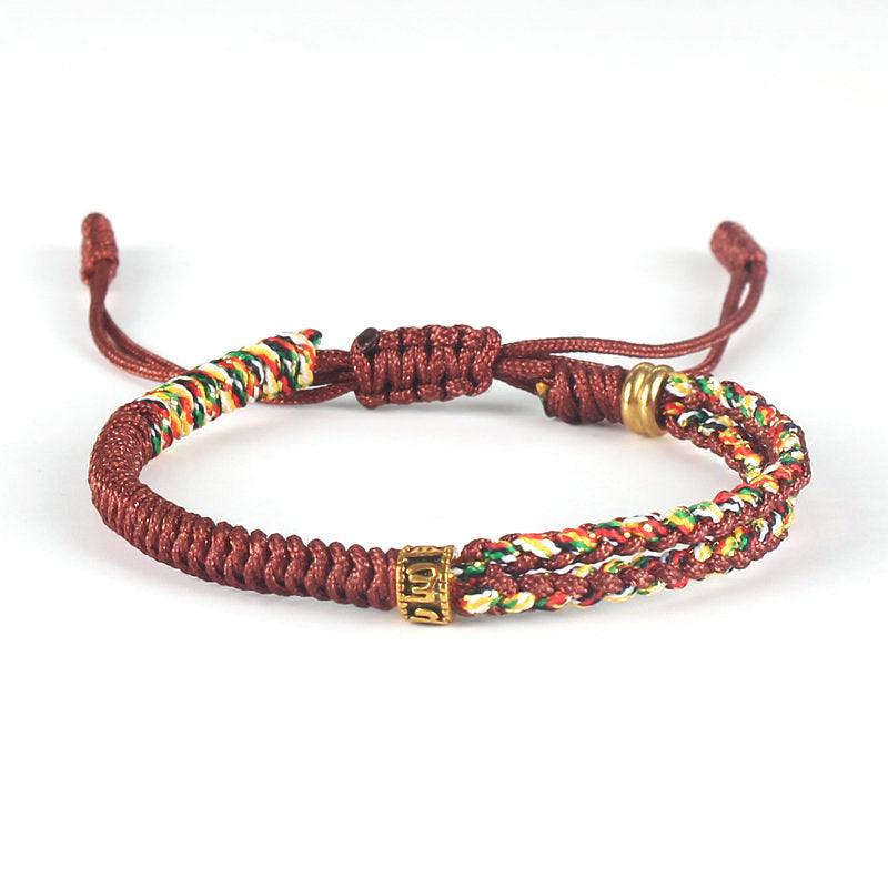 Full view of Tibetan-style brown woven bracelet with multicolored cord and brass accents, symbolizing grounding, warmth, and cultural depth.