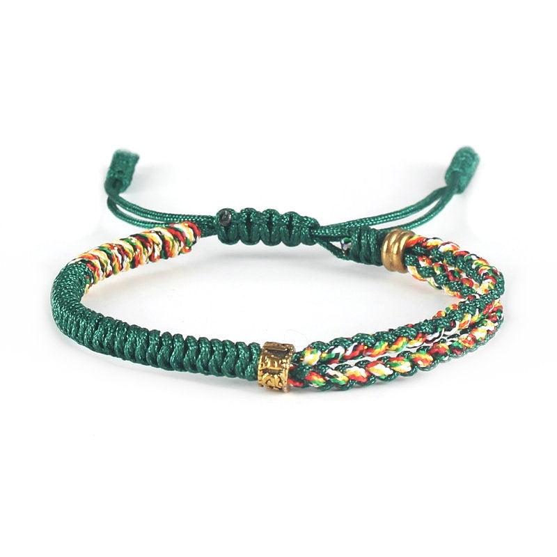 Full view of Tibetan-style green woven bracelet with multicolored cord and brass accents, symbolizing growth, balance, and cultural heritage.