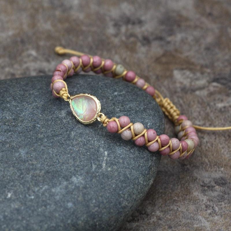 Full view of a gemstone bracelet with a central iridescent stone, surrounded by soft pink natural beads.