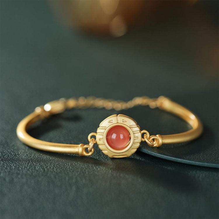 Full view of a gold bracelet featuring a central red agate stone, symbolizing prosperity and protection.