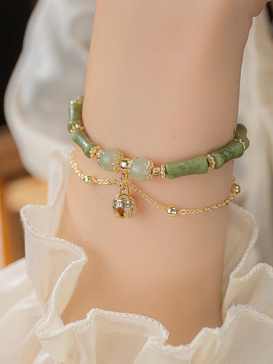 Full view of a jade bracelet with delicate green hues, showcasing a gold chain with a small charm.