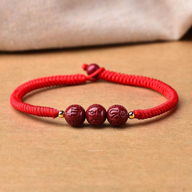 Full view of a red cord bracelet with three cinnabar beads, symbolizing protection and good fortune.
