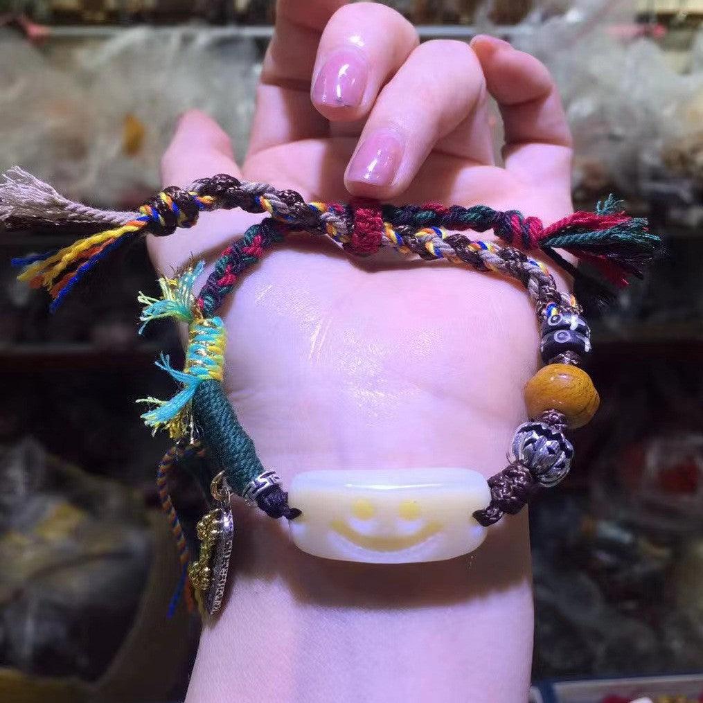 Full view of bracelet featuring a smiling jade centerpiece and vibrant woven cord, symbolizing joy and positivity.