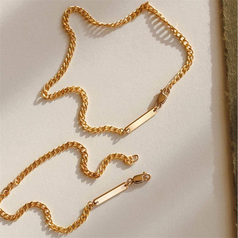 Gold chain necklace with minimalist design displayed on a neutral background, showcasing its sleek and elegant style.