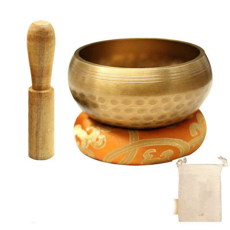 Handcrafted brass bowl with a wooden mallet and embroidered cushion, showcasing traditional Tibetan craftsmanship and attention to detail.