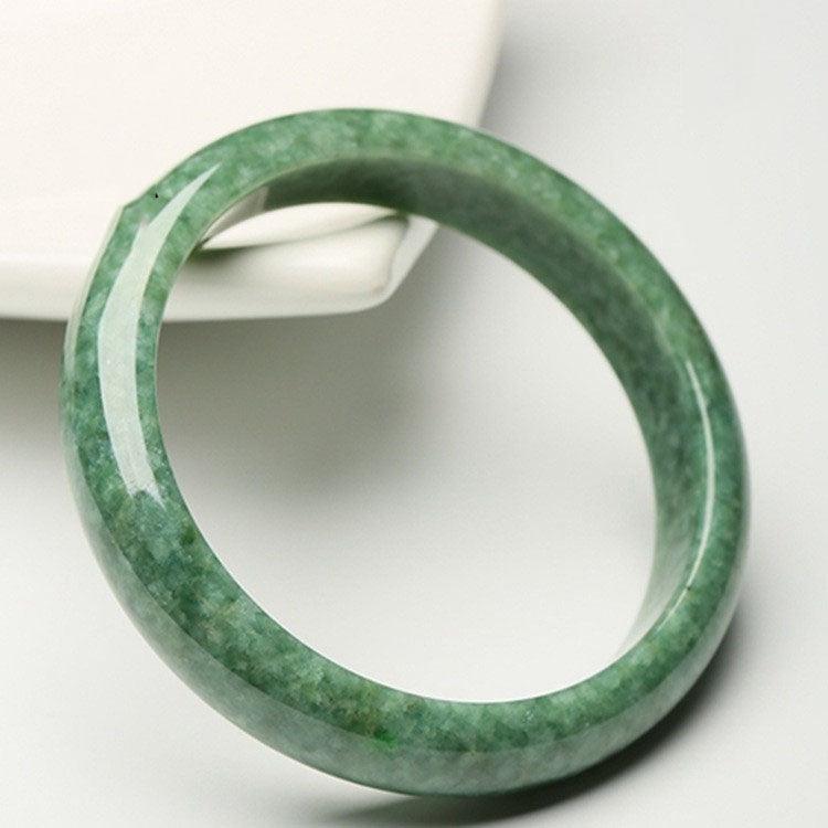 Handcrafted jade bangle, revered for its calming and grounding properties, often worn to promote balance and inner peace.