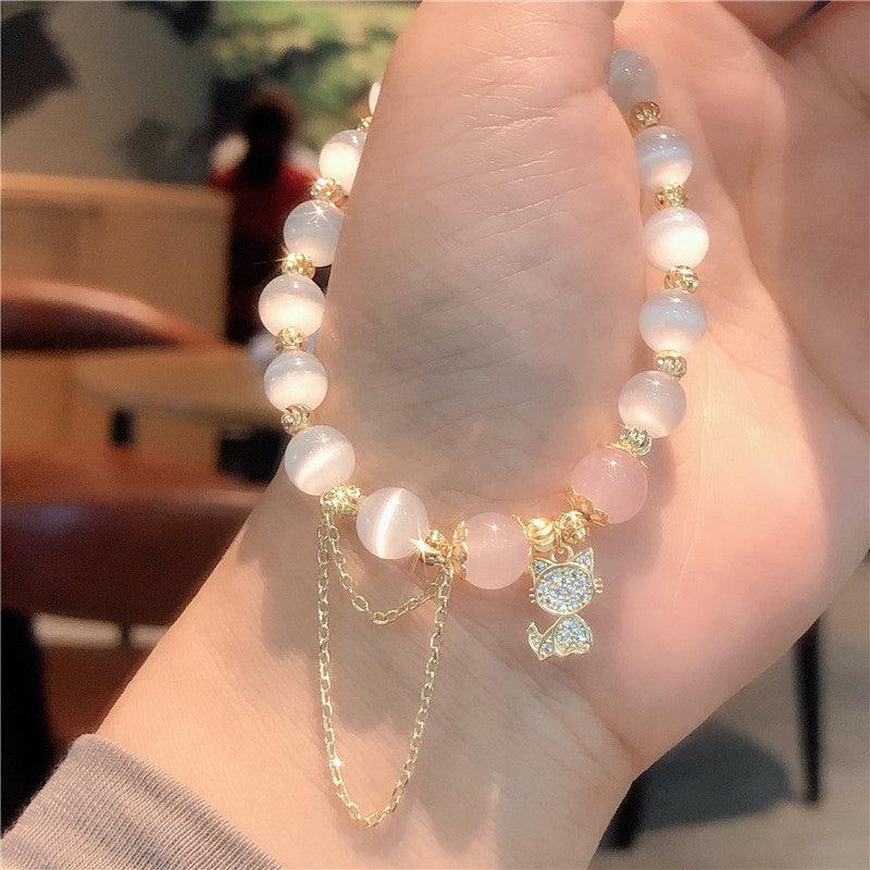 Handmade pink gemstone bracelet with a detailed gold cat charm, showcasing intricate craftsmanship and attention to elegance.