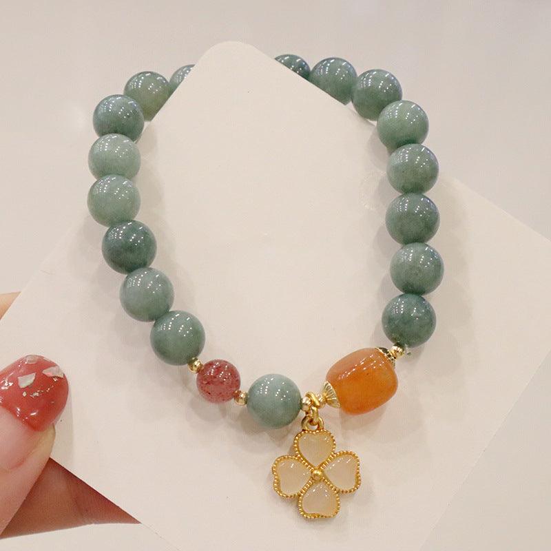 Jade bracelet featuring a lucky four-leaf clover charm, often worn in Chinese culture for prosperity and good fortune.