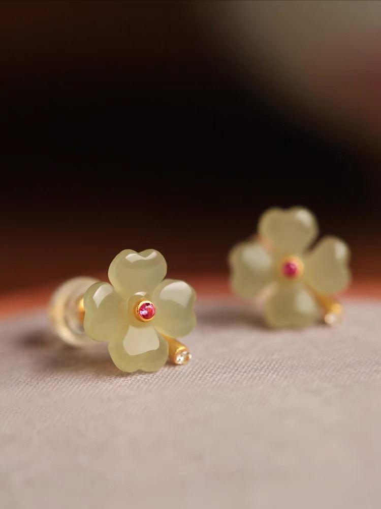 Jade floral earrings featuring a small red gemstone at the center, accented with gold detailing, perfect for adding a touch of natural beauty.