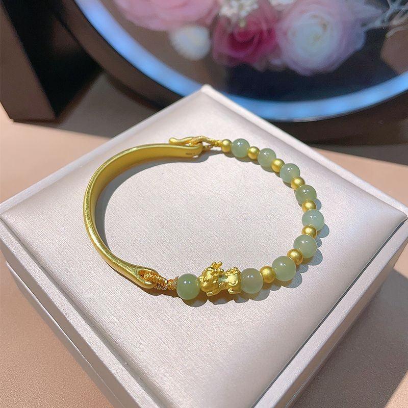 Luxurious bracelet with smooth green jade beads and gold-plated accents, showcasing traditional craftsmanship and modern elegance.