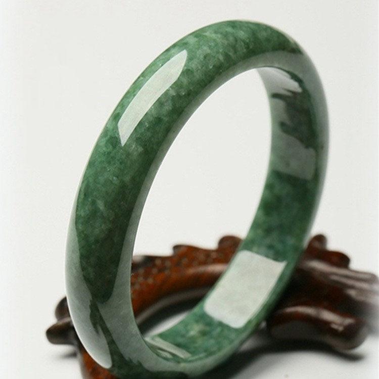Polished green jade bangle with natural marbling, symbolizing purity, protection, and harmony in traditional Chinese culture.