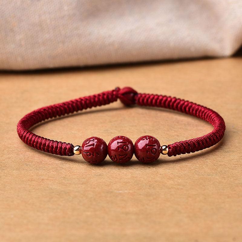 Red braided cord bracelet with cinnabar beads, carrying blessings and spiritual peace.