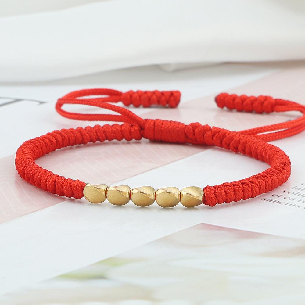 Red cord bracelet with gold beads, symbolizing protection and prosperity. The vibrant red thread combined with elegant golden accents makes this a meaningful accessory.