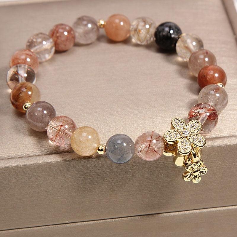 Rutilated quartz beads in warm earth tones with a gold flower charm, perfect for adding a natural elegance to any outfit.