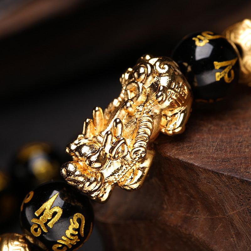 Six-Word Mantra bracelet with black and gold beads, adorned with a Pixiu charm, offering spiritual defense and wealth attraction.
