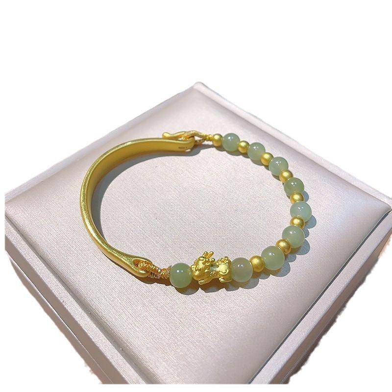 Smooth and polished gold bracelet with jade beads, highlighting fine craftsmanship and traditional elegance in jewelry design.
