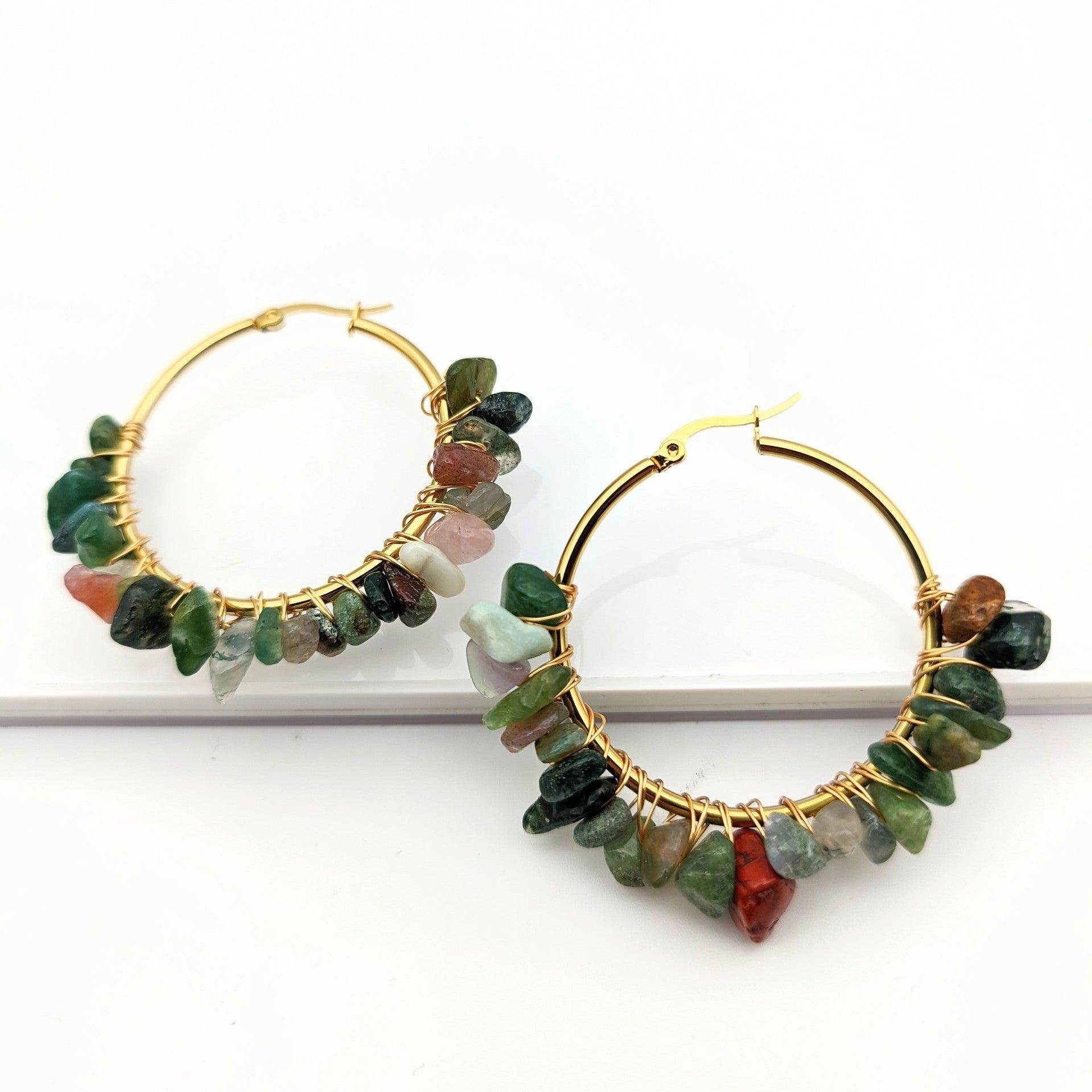 These earrings feature golden hoops paired with natural green stones, symbolizing the vitality and growth of nature. Green gemstones are often seen as symbols of balance and health, bringing a sense of inner peace, making them ideal for wearers looking to connect with nature's energy.