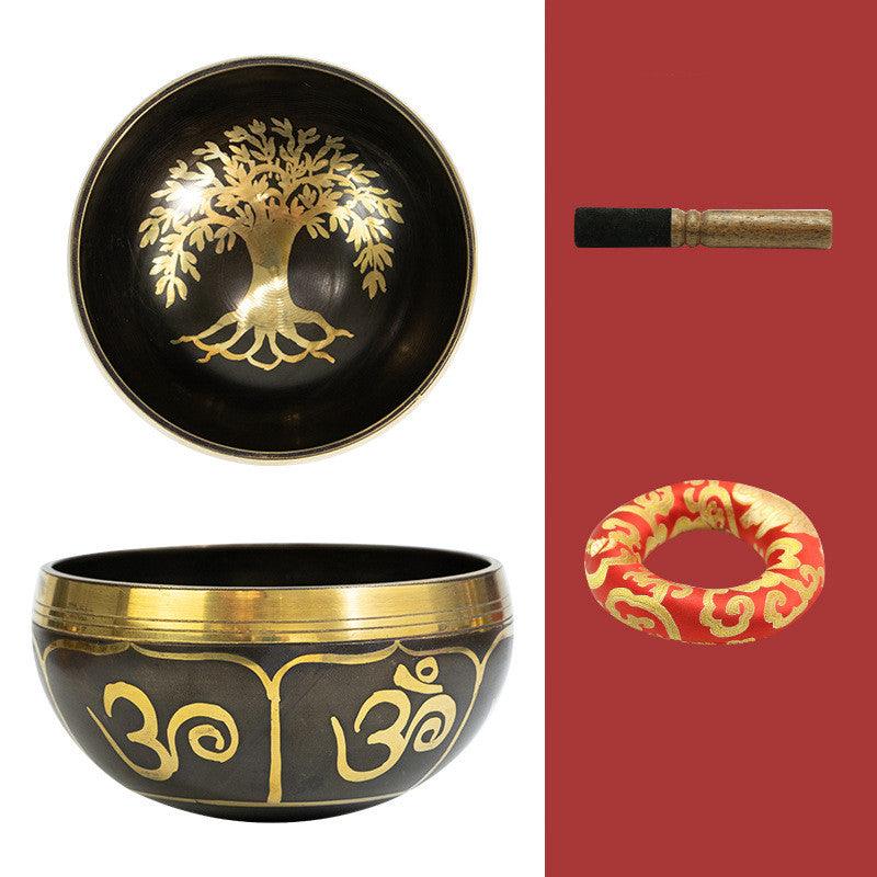 Tibetan singing bowl with intricate ‘Tree of Life’ and ‘Om’ symbols, set with a mallet and cushion, representing growth, spirituality, and universal energy.