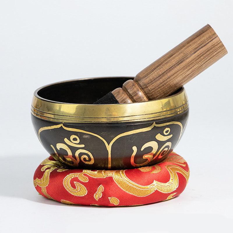 Traditional Tibetan singing bowl with wooden mallet, displayed on a vibrant red cushion, symbolizing mindfulness and spiritual balance.