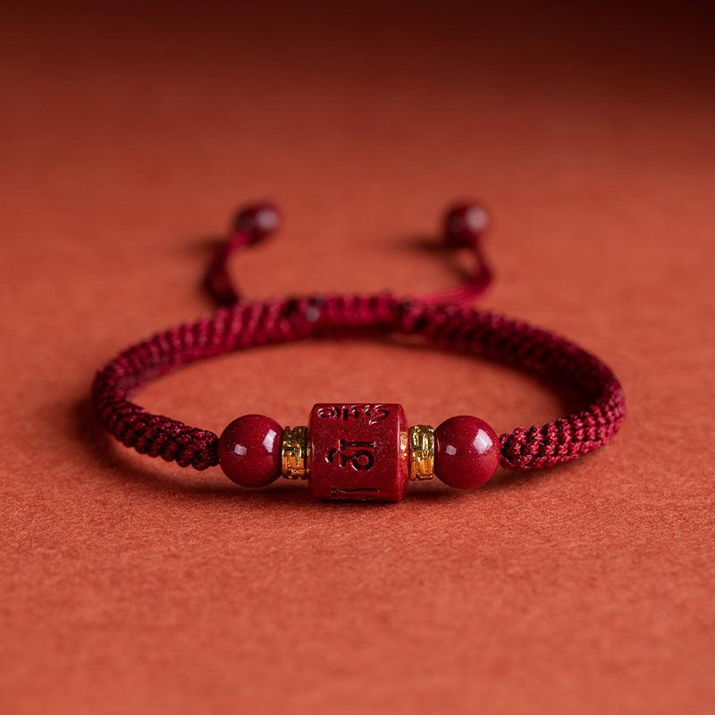 Vermilion red string bracelet with a cylindrical cinnabar bead inscribed with the Six-Word Mantra, symbolizing protection and inner peace. Ideal for wearers seeking to integrate Buddhist wisdom.